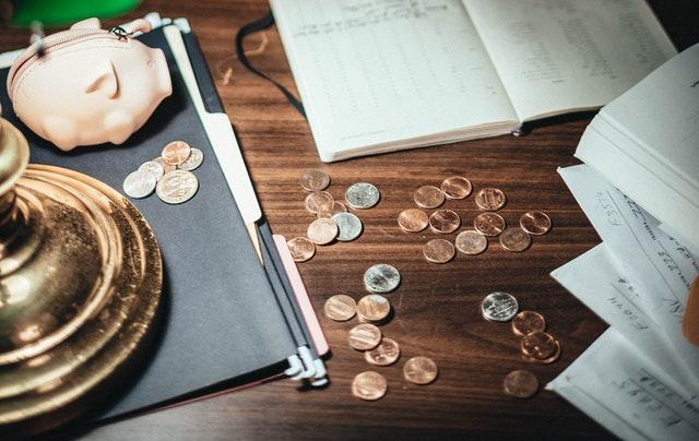 A piggy bank and coins on the table representing a problem of how to choose between a house and a condo in Tucson.